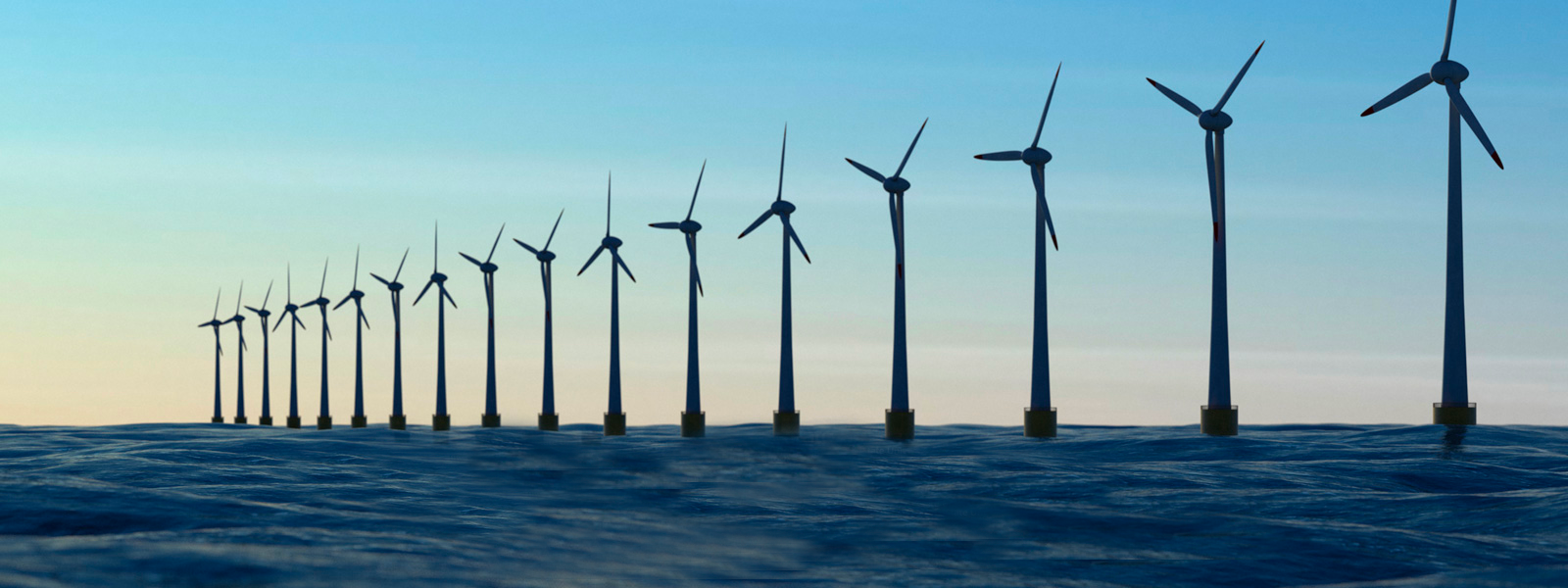 Row of offshore wind turbines standing in open ocean water under a clear blue sky